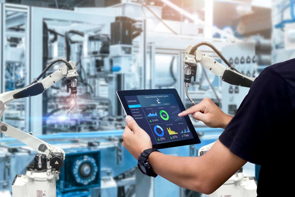 An engineer using a tablet to control robotic machinery illustrates a use case for operational technology security